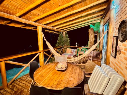 a porch with a hammock and a table and chairs at Rancho do Lagarto Pedra Azul in Domingos Martins
