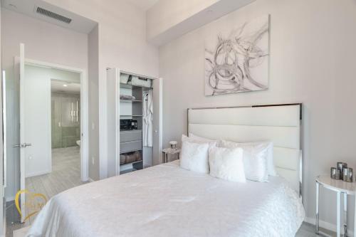 a white bedroom with a large bed with white pillows at Lumiére Penthouse in Miami
