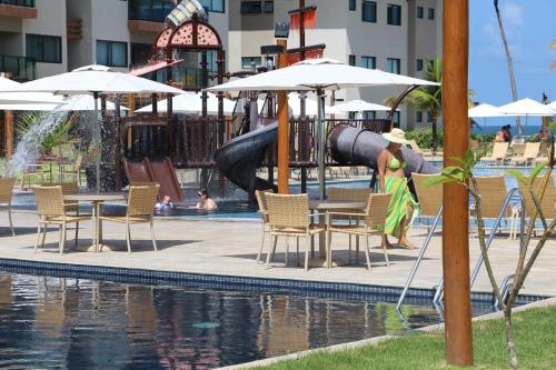 a woman standing in front of a pool with a water park at Refeições inclusa - Polinesia Resort - Porto de Galinhas - Apartamentos com somente 1 opção de Térreo com Piscina Privativa - Acesso ao Hotel Samoa in Porto De Galinhas