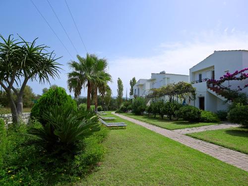 a garden with palm trees and a white building at Mousses Apartments & Studios in Kissamos