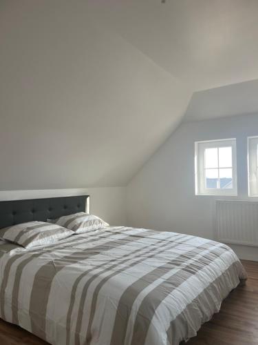 a white bedroom with a bed and a window at Duplex moderne à 10 minutes de Colmar in Wintzenheim