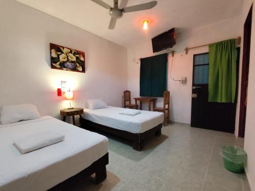 a room with two beds and a table and a television at Alojamiento Ya'ax Nah in Playa del Carmen