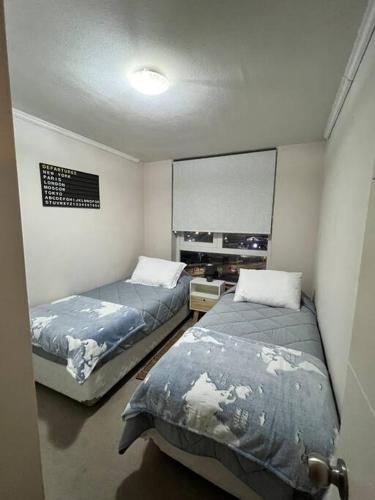 a room with two beds in a room at Amplio Departamento Parque Urbano in Concepción