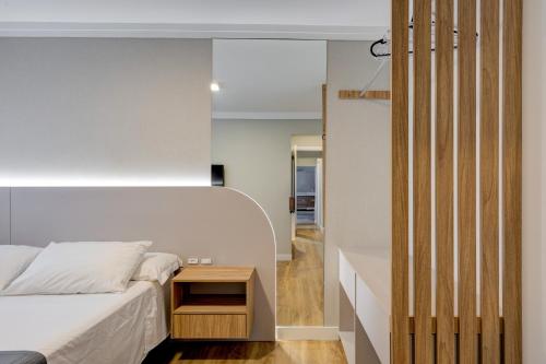 une chambre avec un lit blanc et une table de chevet dans l'établissement Luxo com Vista mar lateral em todos os cômodos, à Balneário Camboriú