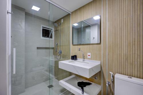 une salle de bain avec un lavabo blanc et une douche dans l'établissement Luxo com Vista mar lateral em todos os cômodos, à Balneário Camboriú
