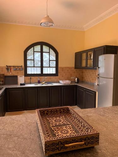 a kitchen with black cabinets and a white refrigerator at Locanda House, Marrakech Sidi Ghiat in Marrakech
