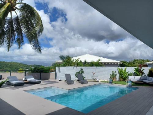 a swimming pool with chairs and a palm tree at Kasa Créole in Les Trois-Îlets