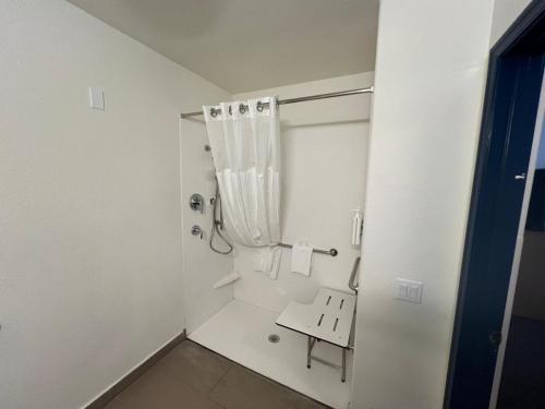 a white bathroom with a shower and a bench at Spark by Hilton Phoenix-Glendale-Peoria in Glendale