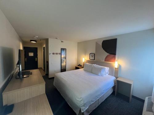 a hotel room with a white bed and a desk at Spark by Hilton Phoenix-Glendale-Peoria in Glendale