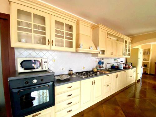 a kitchen with white cabinets and a black stove top oven at Casa Luca in Forza dʼAgro