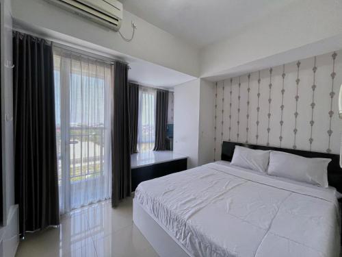 ジョグジャカルタにあるApartement Taman Melati by THE TRUSTの白いベッドと大きな窓のある寝室