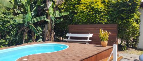 a wooden deck with a swimming pool and a chair at Cabana ferrugem pool in Garopaba