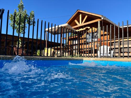 a swimming pool in front of a wooden house at Cabaña La campana in Hijuelas