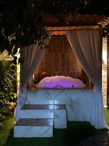 a bed in a room with a curtain at Chalé Rochat Maresias in Maresias