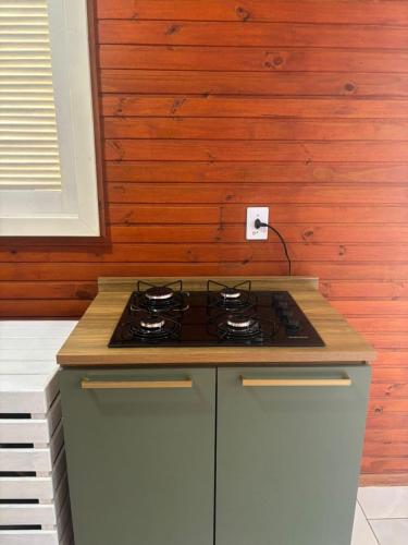 a stove top in a kitchen with a wooden wall at Chalé de 1 quarto, com estacionamento, a 5 min da praia! in Passo de Torres