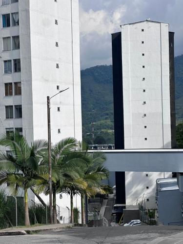 a large white building with palm trees in front of it at Apartamento Norte de Armenia Salida para Salento y Filandia in Armenia