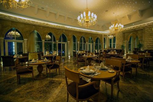 a restaurant with tables and chairs and chandeliers at Grand Millennium Sulaimani in As Sulaymānīyah
