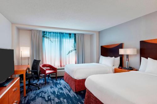 a hotel room with two beds and a desk and a television at Fairfield Inn Suites Indianapolis Downtown in Indianapolis