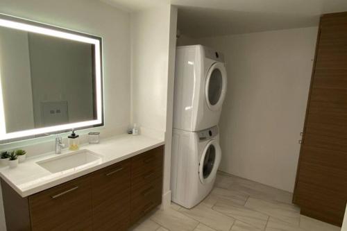 a bathroom with a washing machine next to a sink at Luxury Penthouse Loft w POOL GYM AMERICANA in Glendale