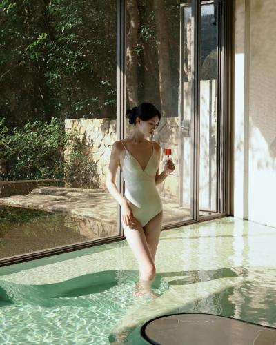 a woman in a bathing suit standing in a swimming pool at Yakamoz Qianchuan Hotel in Lin'an