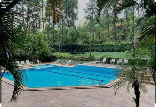 a large swimming pool with blue water in a yard at Flat no coração de Alphaville in Barueri
