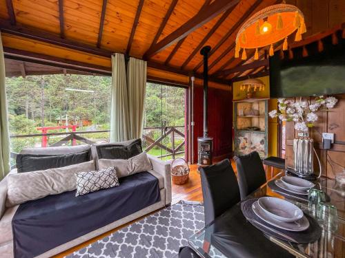 a living room with a couch and a glass table at Pousada Jardim do Buda com Café e Piscina in Urubici