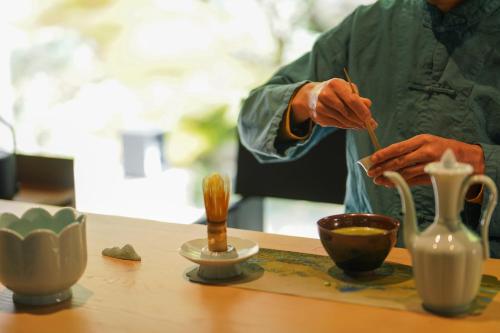 a person is preparing a bowl on a table with vases at Yakamoz Qianchuan Hotel in Lin'an