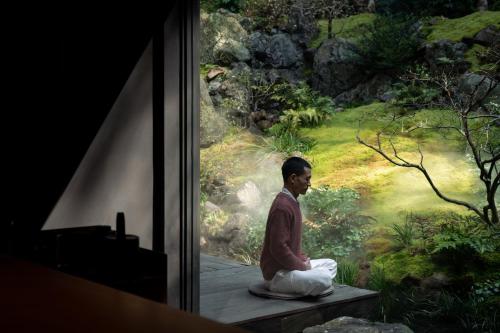 a woman sitting on a bench in front of a painting at Yakamoz Qianchuan Hotel in Lin'an