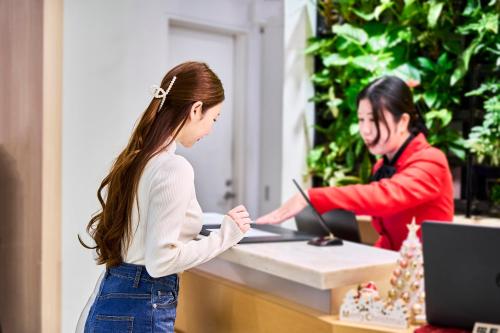 a young girl standing in front of a cash register at Hotel Sobial Osaka Dome in Osaka