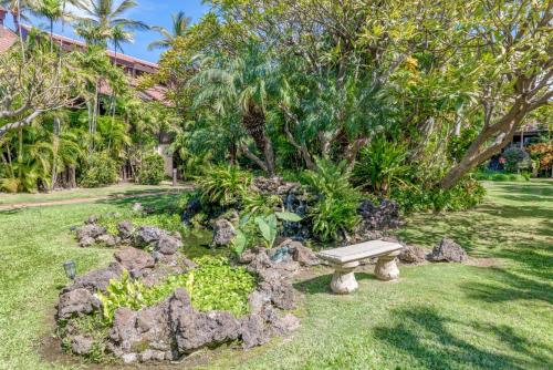a park bench in a garden with rocks and trees at Kihei Resort 202 · KRS 202 Family Getaway 2BD w AC Pool Beach in Kihei