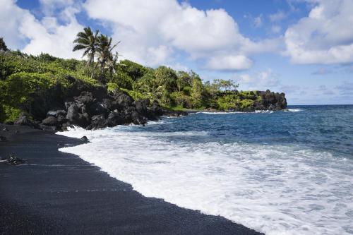 a black sand beach with palm trees and the ocean at Kihei Resort 202 · KRS 202 Family Getaway 2BD w AC Pool Beach in Kihei