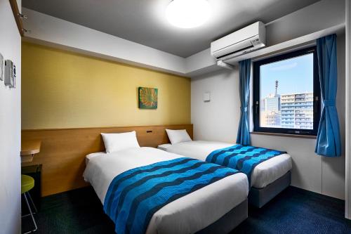 a hotel room with two beds and a window at Hotel Sobial Osaka Dome in Osaka