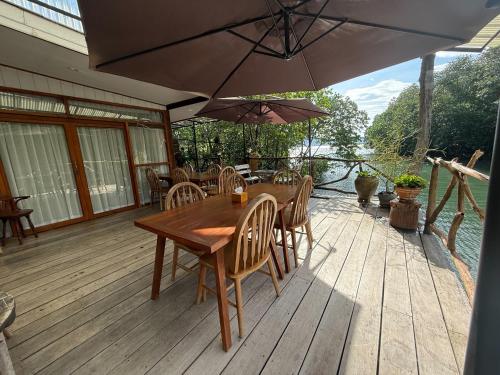 a wooden table with chairs and an umbrella on a deck at Baan Chan Lay Koh Chang in Ko Chang