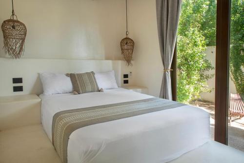 a bedroom with a white bed and a window at COCCOLOBA in Holbox Island