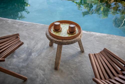 a table with two cups on it next to a pool at COCCOLOBA in Holbox Island