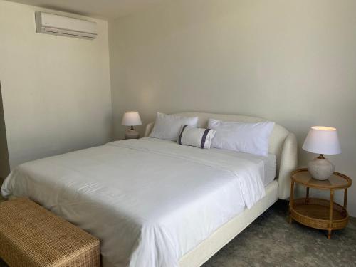 a bedroom with a white bed with two lamps at The Palm Bay Club Lodge in Nagua