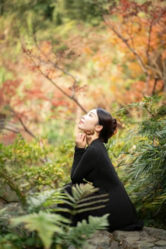 a woman sitting on a rock in a forest at Yakamoz Qianchuan Hotel in Lin'an