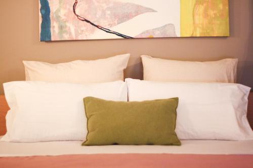 a bed with white pillows and a green pillow at Akis Apartments in Paleokastritsa