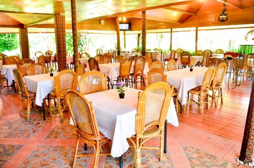 a dining room with tables and chairs with white tablecloths at Toraja Misiliana Hotel in Rantepao