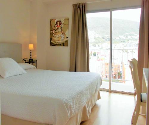 Un dormitorio con una cama blanca y una ventana grande. en Apartamentos Bruja, en Santa Cruz de Tenerife