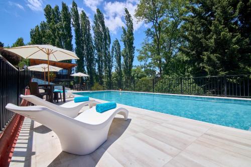 a swimming pool with two white chairs next to a swimming pool at mirabosque new aparments 4 in Osorno