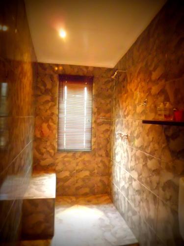 a stone bathroom with a shower with a window at Top House Bed and Breakfast in Ladybrand