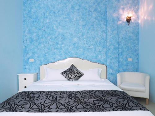 1 dormitorio azul con 1 cama y 1 silla en Siang Ti Ya Homestay, en Kenting