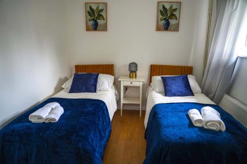 two beds in a room with blue and white sheets at Milton Keynes Home - Sleeps 4 - Parking in Milton Keynes