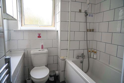 a bathroom with a toilet and a tub and a shower at Milton Keynes Home - Sleeps 4 - Parking in Milton Keynes