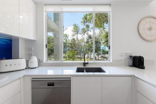 a white kitchen with a sink and a window at Beaches Holiday Apartments - Official Onsite Reception & Check In in Port Douglas