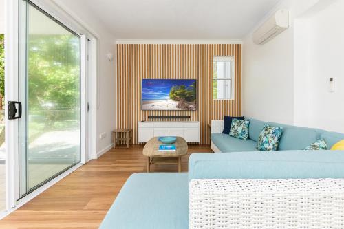 a living room with a blue couch and a table at Beaches Holiday Apartments - Official Onsite Reception & Check In in Port Douglas