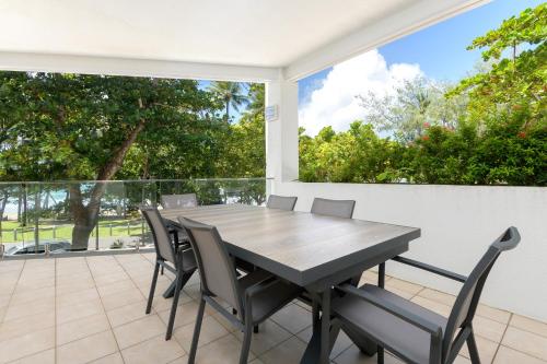 a wooden table and chairs on a patio at Beaches Holiday Apartments - Official Onsite Reception & Check In in Port Douglas
