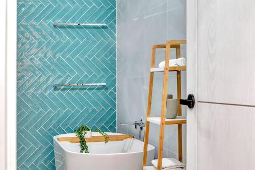 a bathroom with a white tub and a blue wall at Gathering Tides - For Group Getaways by the Beach in Normanville
