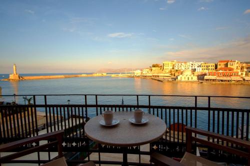 una mesa con 2 tazas de café en un balcón con vistas al agua en Erietta Suites, en La Canea